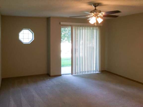 a living room with a ceiling fan, a sliding glass door with vertical blinds, and a window