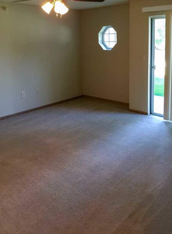 a living room with a carpeted floor and a ceiling fan