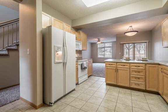 A kitchen with a refrigerator, oven, and cabinets.