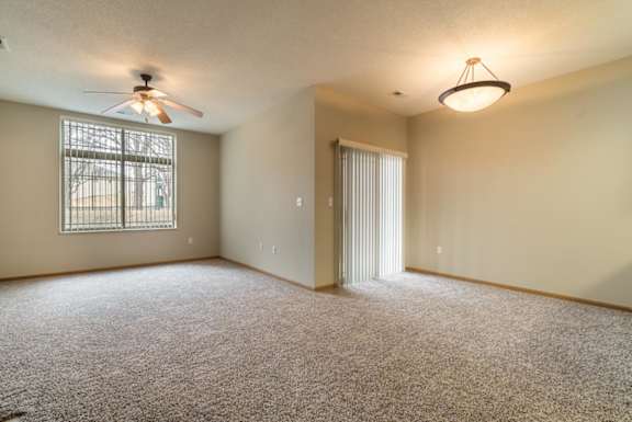 A room with a ceiling fan and carpeted floor.