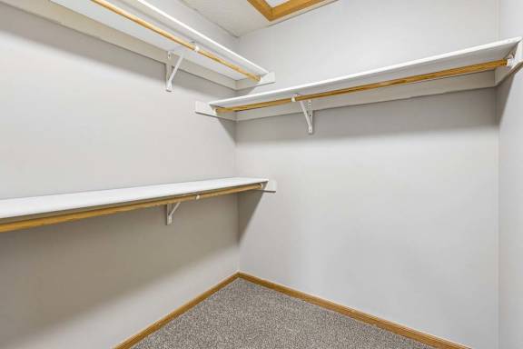 Spacious walk-in closet featuring built-in shelves on multiple walls.
