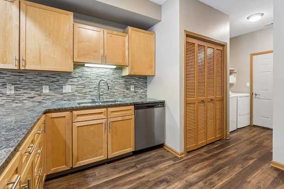 Kitchen area with granite counters, tile backsplash, and adjacent laundry closet.