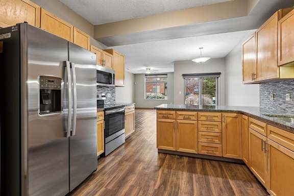Modern open-concept kitchen with island, stainless steel range, and wood-style floors.
