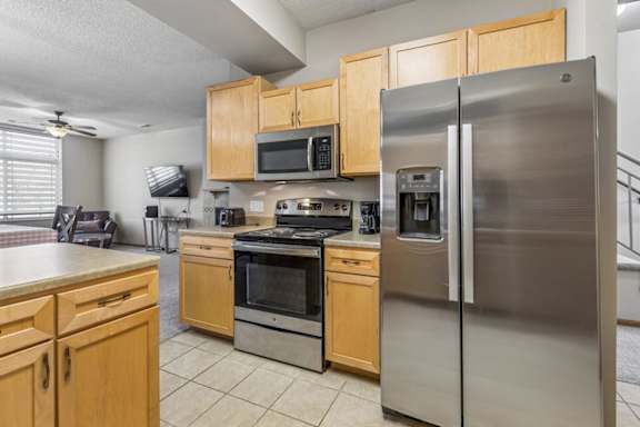 A kitchen with a stainless steel refrigerator and wooden cabinets.