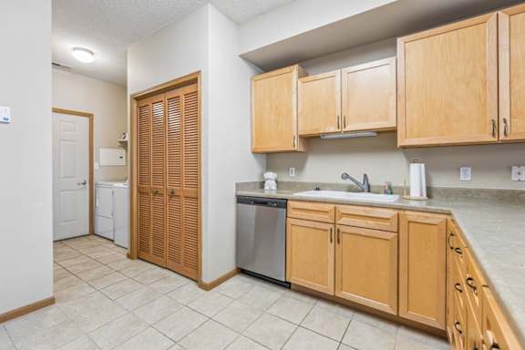 Functional apartment kitchen with light wood cabinetry, laminate countertops, tile flooring, and dishwasher.
