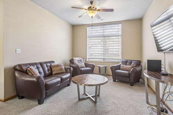 Spacious apartment living room with plush carpet, large window, fireplace, and open sightlines to the dining area.