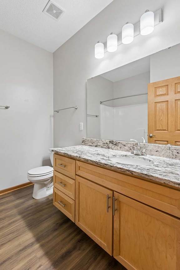 Bathroom with double vanity, granite countertop, and wall-mounted lighting.