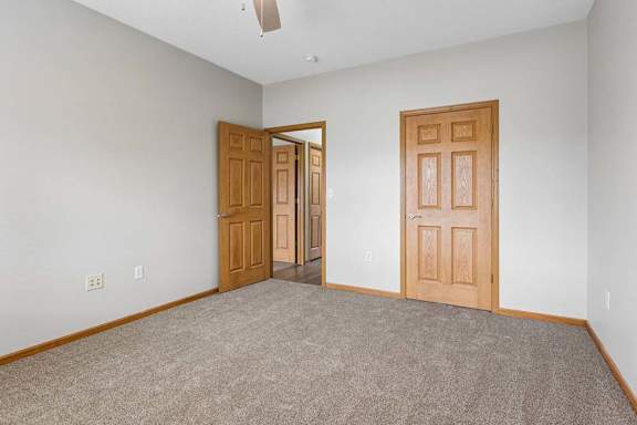 Bedroom with carpeted floor, closet access, and hallway door.