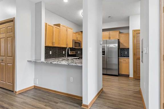 Modern apartment kitchen featuring granite countertops and stainless steel refrigerator.