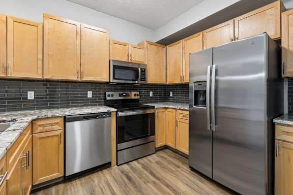 Modern apartment kitchen with stainless steel appliances and wood cabinetry
