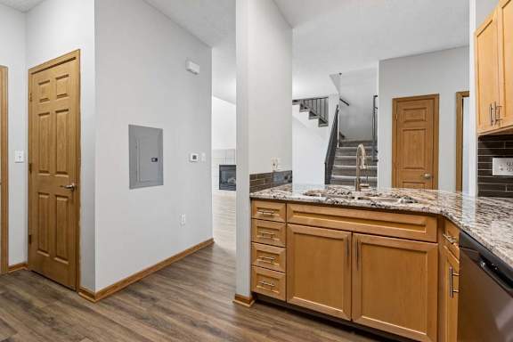 Kitchen area featuring wood cabinets, granite counters, and adjacent hallway.