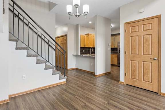 Open-concept entry with stairway, wood flooring, and adjacent kitchen.