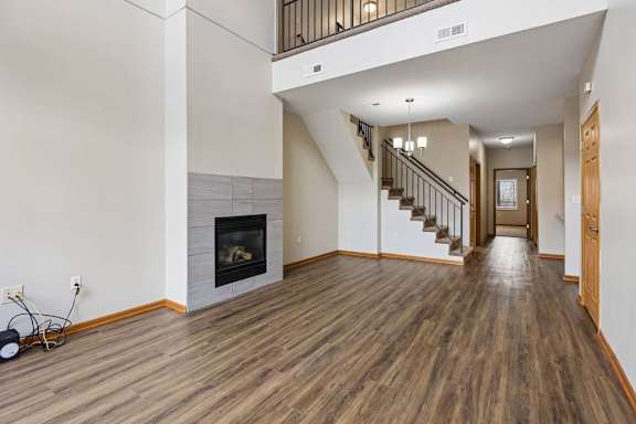 Spacious living area featuring a fireplace, open staircase, and wood flooring.