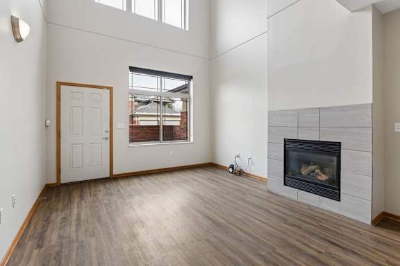 Open living room with gas fireplace, vaulted ceiling, and wood-style flooring.