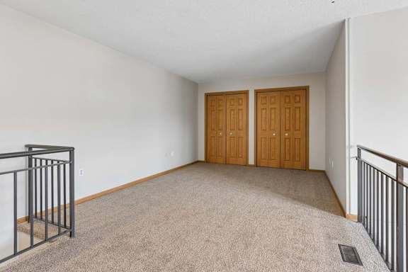 Carpeted upper-level room with railing overlook and double closet doors.
