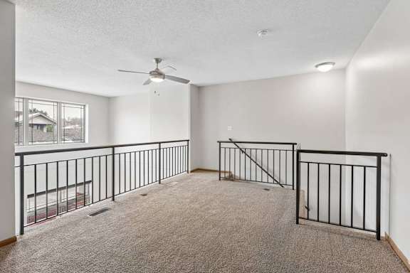 Spacious loft area overlooking the lower level with carpet and railing.