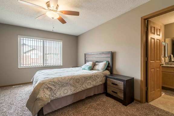 Master bedroom with attached bathroom and ceiling fan at Southwind Villas in southwest Omaha in La Vista, NE, 68128