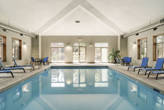 a swimming pool with blue lounge chairs around it