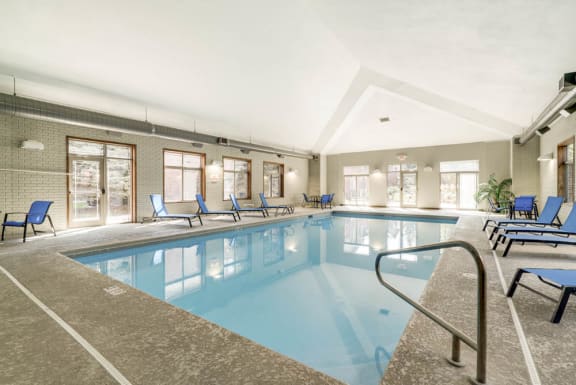 a swimming pool with blue chairs and a railing around it