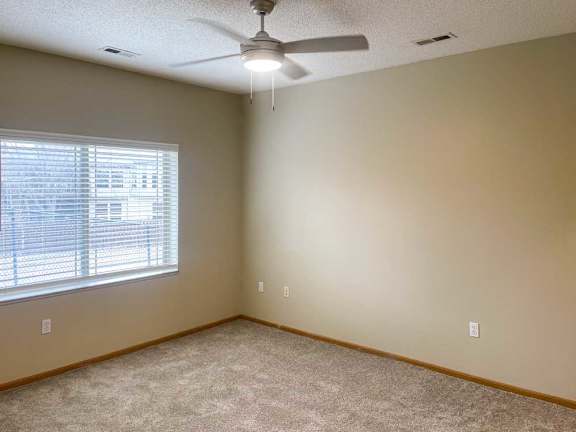 a bedroom with a ceiling fan and a window with blinds