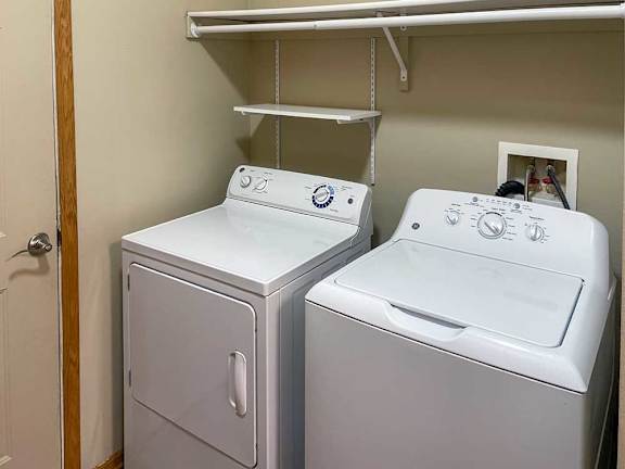 a white washing machine and dryer side-by-side with overhead storage shelves
