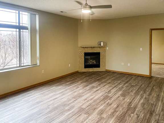 a living room with a corner fireplace, luxury vinyl tile flooring, and a ceiling fan