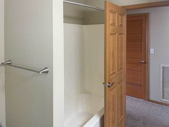 a bathroom with a tub shower and a towel rack