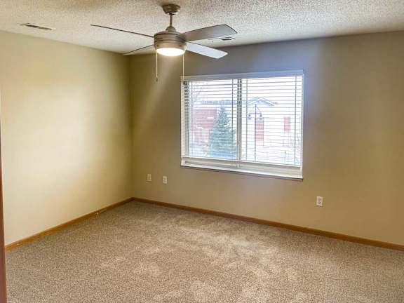 a bedroom with a ceiling fan and a window with blinds