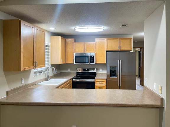 a kitchen with wooden cabinets and stainless steel appliances