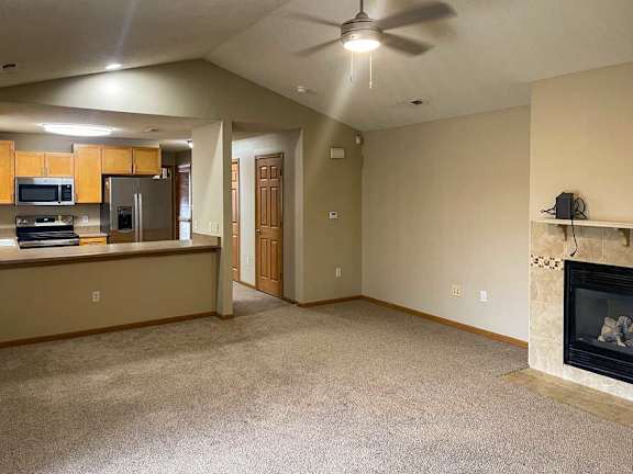 a living room with a fireplace and a kitchen area in the background