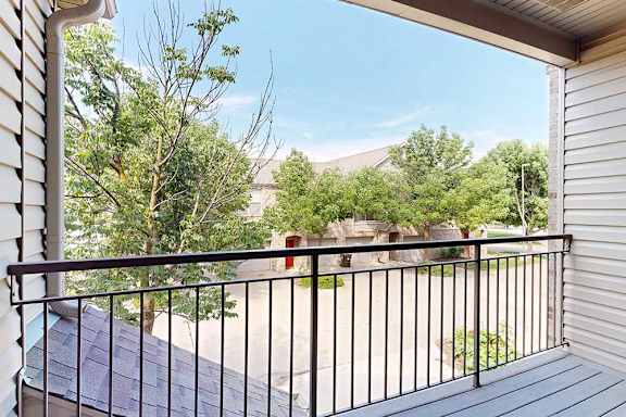 A balcony with a black railing overlooks nearby apartments at Stone Creek Villas.