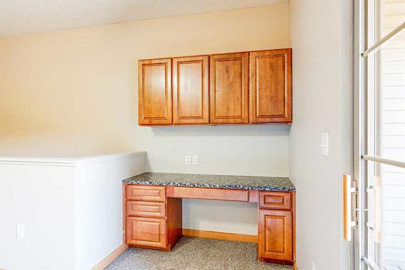 A built-in desk with wooden cabinets and a granite counter in the living room.