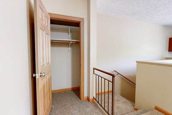 A coat closet at the top of the stairs from the private entry, with built-in shelves and hanging space.