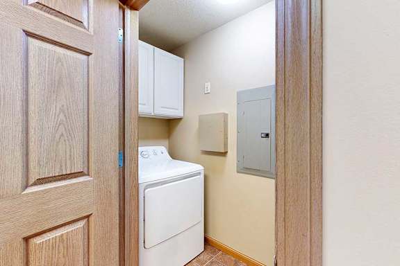 A laundry room with full-sized washer and dryer with overhead cabinets for storage.