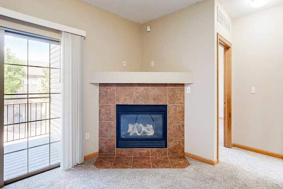 A living room with a fireplace next to the sliding glass door to the balcony.