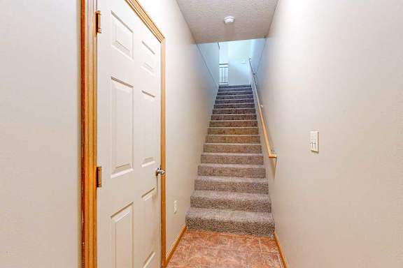 An entryway with a door to the attached garage, and a staircase that leads up to the living room.