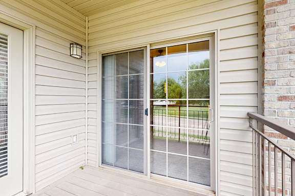 A balcony with a sliding glass door to the primary bedroom, and a windowed door to the kitchen.