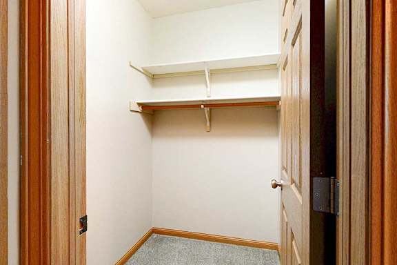 A walk-in closet with two shelves and hanging space.