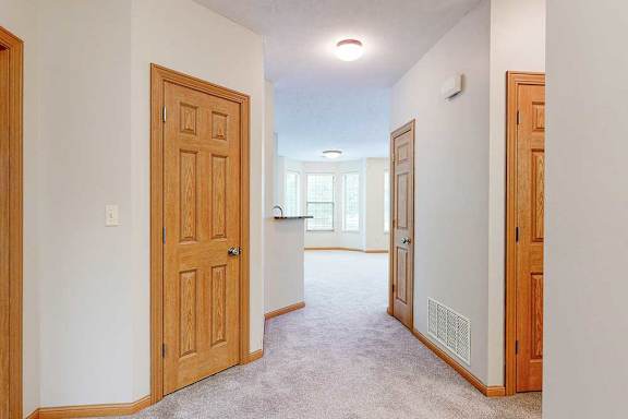A hallway leading from the front entrance to the living room, with several closet doors.