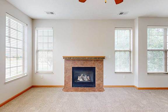 A living room with a fireplace and several windows.