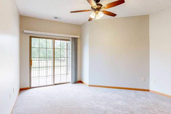 A bedroom with a ceiling fan and a sliding glass door to a balcony.