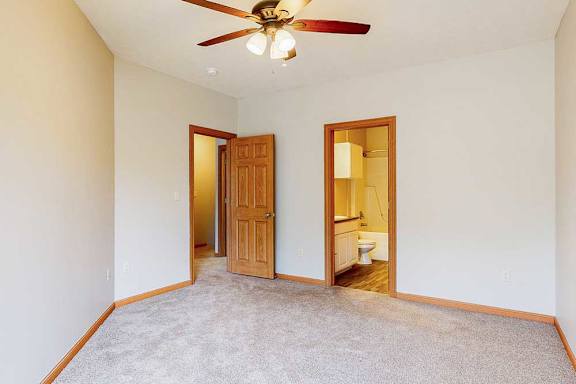 A primary bedroom with a ceiling fan, and an attached bathroom.