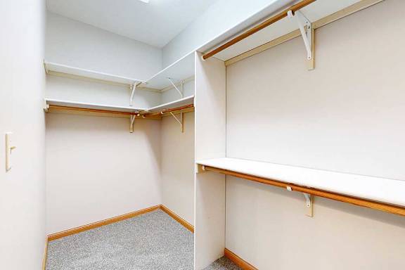 A long walk-in closet with several built-in shelves and hanging space.