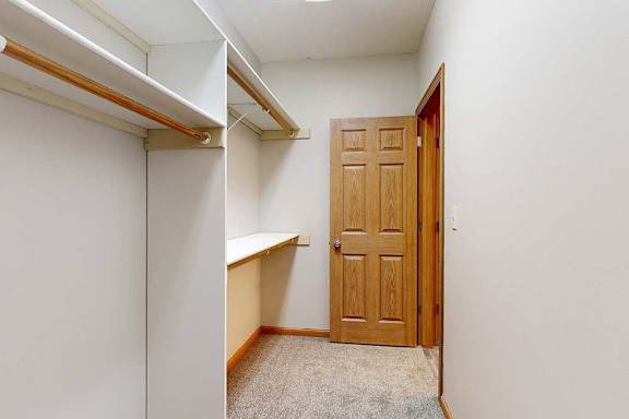 A long walk-in closet with several built-in shelves and hanging space.