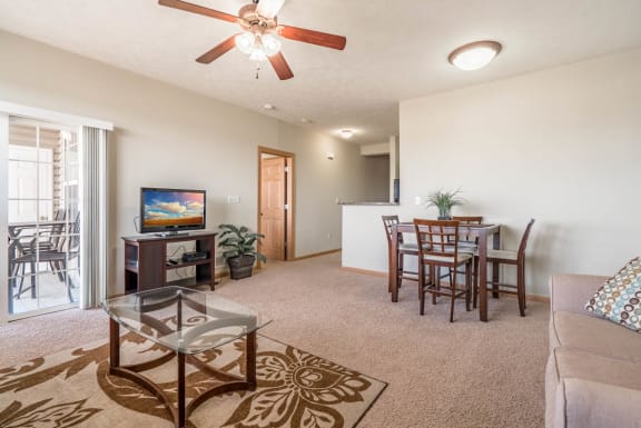 a living room and dining room with a table and a ceiling fan