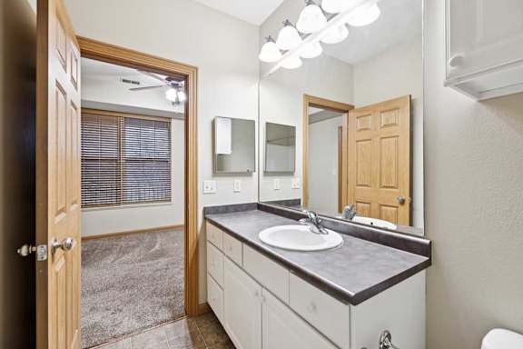 Full bathroom with extended vanity, large mirror, and overhead lighting.