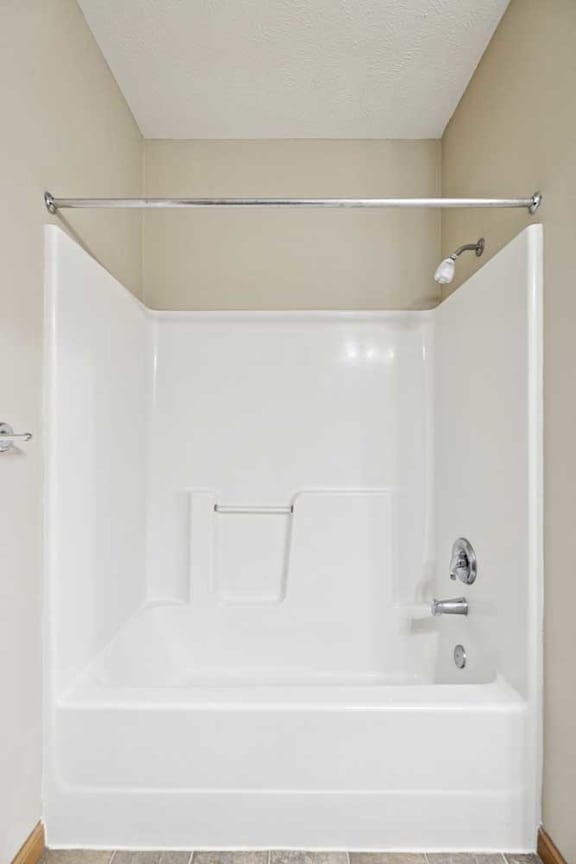 Tub and shower combination with white surround and chrome fixtures.