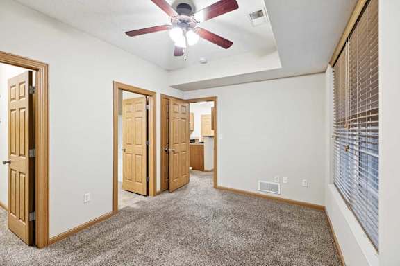 Bedroom with vaulted ceiling, ceiling fan, and open doorway to en-suite bathroom and closet.