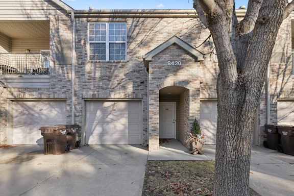 Brick apartment exterior with arched entryway and attached garage.