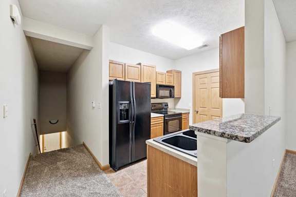 Galley-style kitchen with black refrigerator, oven, microwave, and ample cabinet storage.